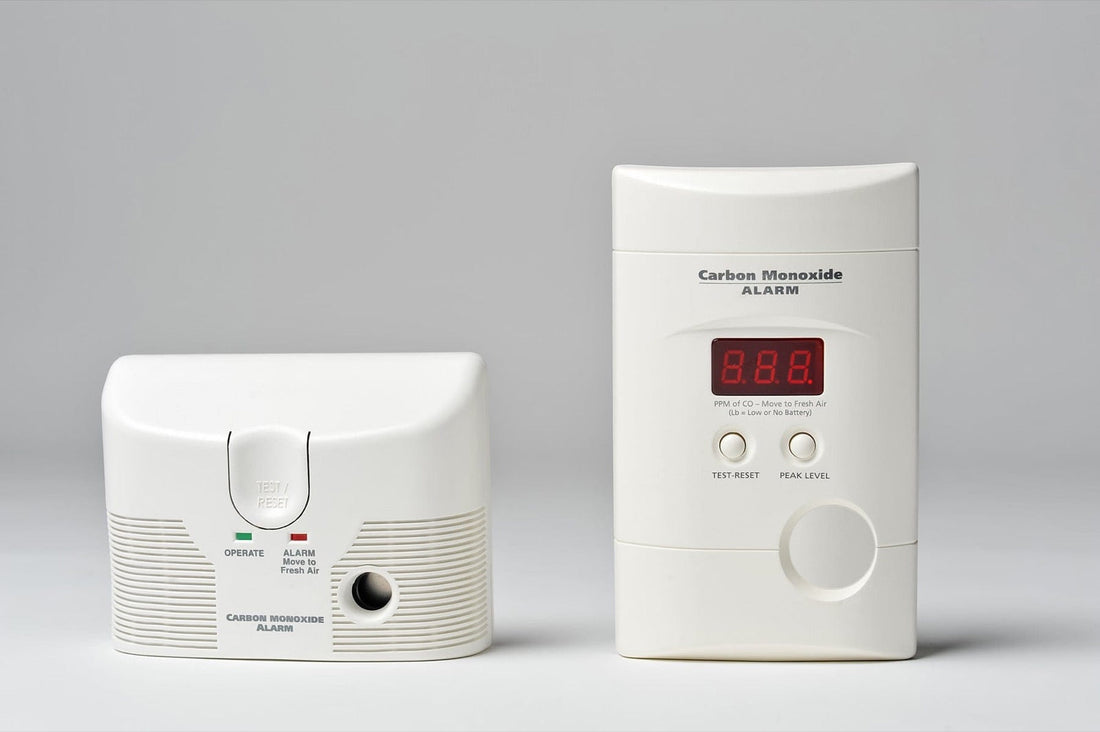 Two white carbon monoxide alarms in front of a white background