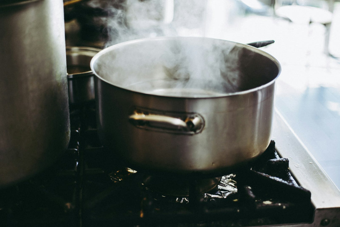 Steam rising from an open stainless-steel pot on a stovetop